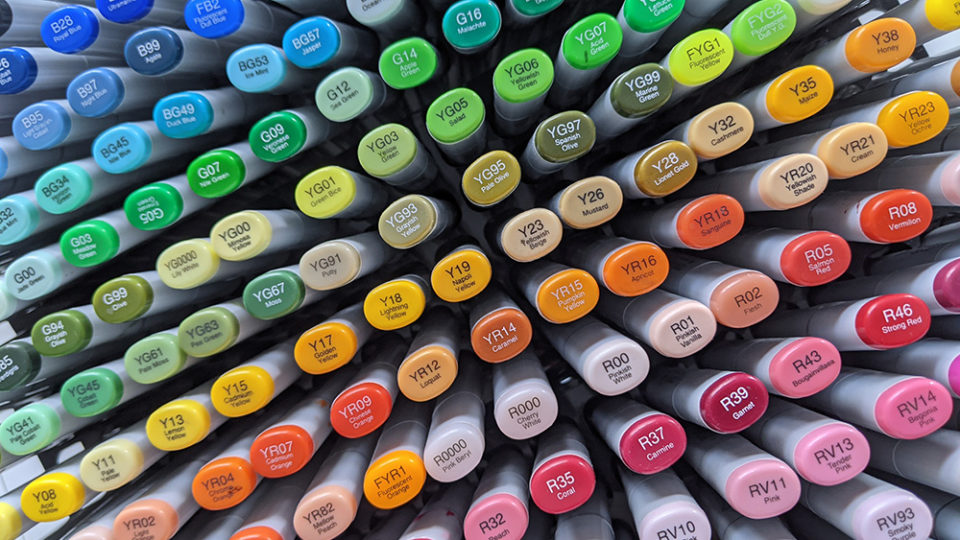 Collection de feutres japonais de la marque Copic. L'image est composée d'une vue du dessus de tous les feutres rangés verticalement. Les bouchons sont colorés, portent la numérotation de chaque feutre. L'ensemble forme un bel arc-en-ciel.